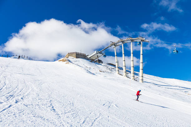 Sciatore sulle piste dell'Abetone con gli impianti di risalita sullo sfondo